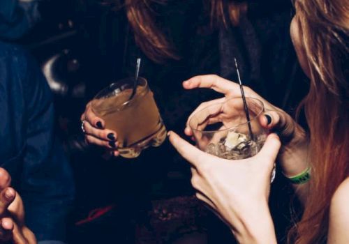 People are enjoying a night out, holding drinks and laughing together in a lively social setting.