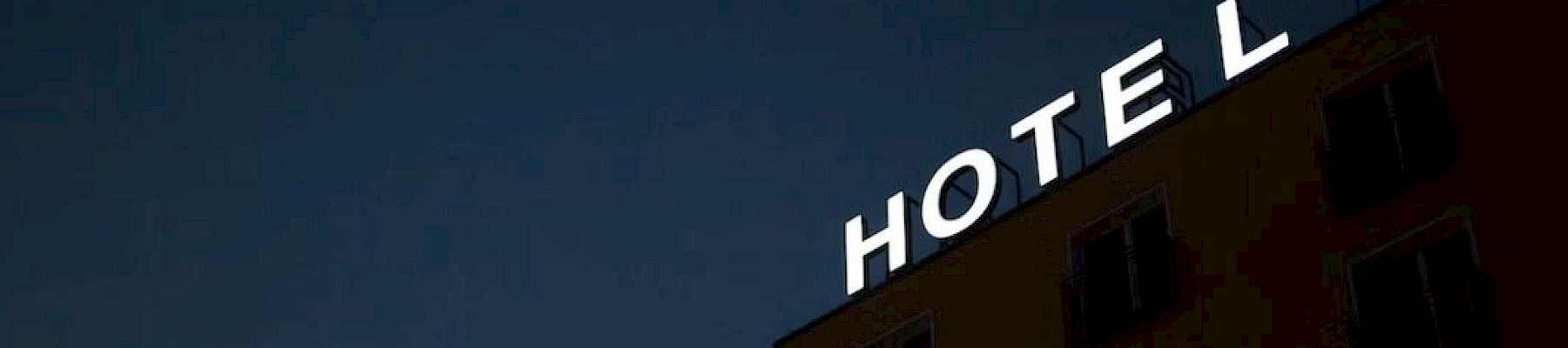 A building shows a partially lit neon sign reading "HOTEL" against a dark sky, with only some letters illuminated.