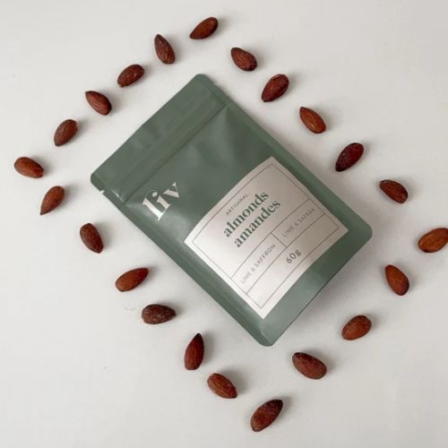 A green package labeled "almonds amandes" is surrounded by a circle of almonds on a white surface.