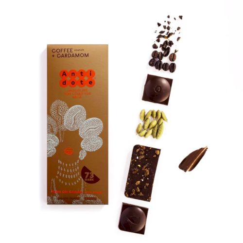 The image shows a coffee and cardamom chocolate bar with its packaging, coffee beans, cardamom pods, and chocolate pieces.