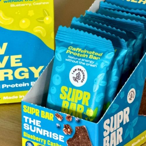 A box of caffeinated protein bars labeled "Supr Bar" in blueberry cashew flavor is displayed.