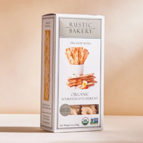 A box of Rustic Bakery Organic Sourdough Flatbread Olive Oil & Sel Gris flavor is shown against a neutral background.