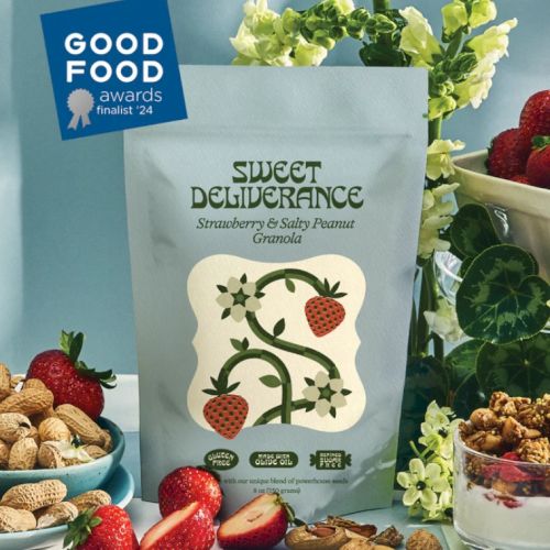 A package of Sweet Deliverance strawberry and salty peanut granola, surrounded by strawberries and peanuts, with a Good Food Awards label.