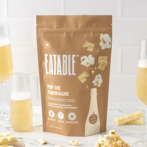 A brown package labeled "EATABLE: Pop the Champagne," featuring popcorn, cheese cubes, and champagne glasses in the background.