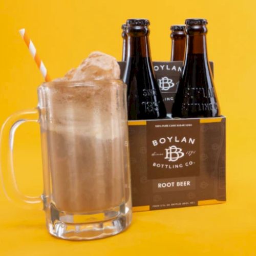 A root beer float in a mug with a straw next to a four-pack of Boylan Bottling Co. root beer bottles on a yellow background.
